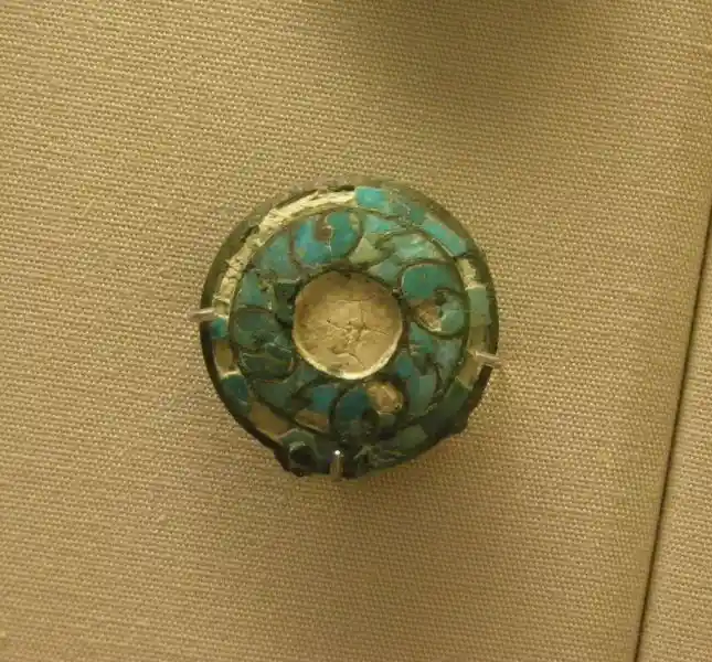 Four swirls around a circle forming a cross on a jade spearhead blade set in a bronze shaft inlaid with turquoise